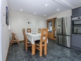 A kitchen with a dining table and chairs at Benlli in Pwllheli