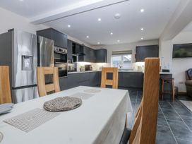 A kitchen with a table and chairs at Benlli in Pwllheli