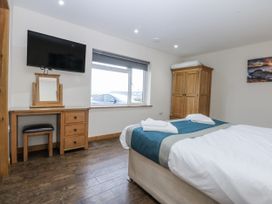 A bedroom with a bed, television, and window at Benlli in Pwllheli