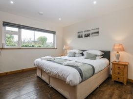 A bedroom with a bed, nightstand, and window at Benlli in Pwllheli