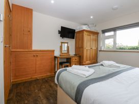 A bedroom with a bed, wardrobe, mirror, and television at Benlli in Pwllheli