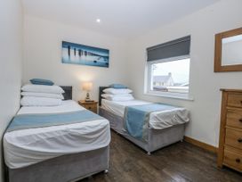 A bedroom with two beds and a nightstand at Benlli in Pwllheli