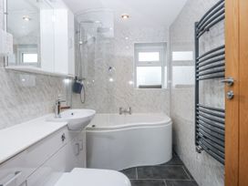 A bathroom with bathtub, wash basin, and towel radiator at Benlli in Pwllheli