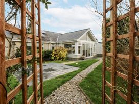 A garden with a gravel pathway and wooden trellis at Benlli in Pwllheli