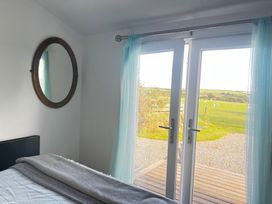A bedroom with a bed and double doors leading to a field at The lodge at Plumstone View in Haverfordwest