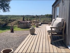 A wooden deck with seating and a hot tub at The lodge at Plumstone View Haverfordwest