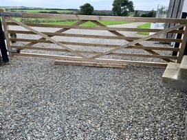 A wooden gate on gravel leading to a field at The lodge at Plumstone View in Haverfordwest