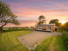 A cabin on a gravel area with trees and grass at The lodge at Plumstone View Letterston