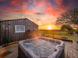 A hot tub next to a wooden building during sunset at The lodge at Plumstone View in Letterston