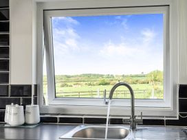A kitchen sink with jars and a window at The lodge at Plumstone View in Letterston