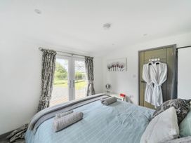 A bedroom with a bed and double doors opening to the outside at The lodge at Plumstone View Letterston