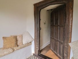 An entrance with a large wooden door and cushions on a stone bench at Ellishayes Farm in Combe Raleigh