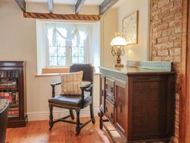 A sitting room with a chair and lamp at Ellishayes Farm in Combe Raleigh