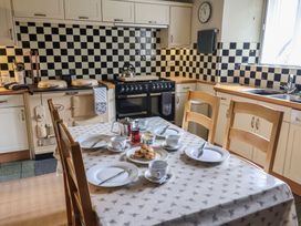 A kitchen with an oven, stove, and a dining table set for tea at Ellishayes Farm in Combe Raleigh