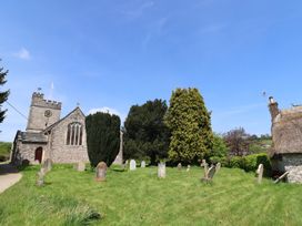 A church with a graveyard and trees at Ellishayes Farm in Combe Raleigh