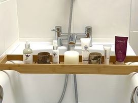 A bathtub with a bamboo tray holding skincare products at The Bark House in Tiverton