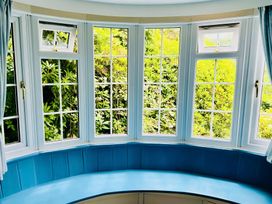 A living room with bay windows and greenery visible at The Bark House in Tiverton