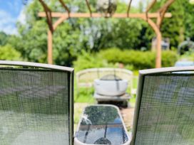 A garden with chairs and a table under a wooden pergola at The Bark House in Tiverton