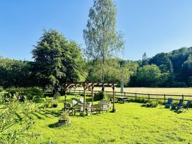 An outdoor seating area with a pergola and trees at The Bark House in Tiverton