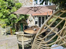 A garden with table and chairs under an umbrella at The Bark House in Tiverton