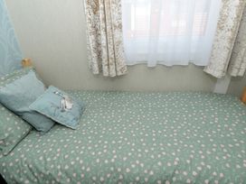 A bed with pillows and a window with curtains at 228b Eighth Avenue Bridlington