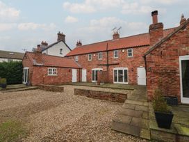 An outdoor view of brick buildings and gravel at Champagne Cottage in Weaverthorpe