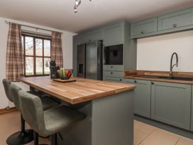 A kitchen with a refrigerator and bar stools at Champagne Cottage in Weaverthorpe