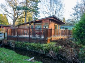 A wooden cabin with a deck near a stream at 6 Waterside in Windermere
