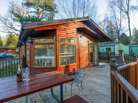 A log cabin with a deck and table at 6 Waterside Windermere