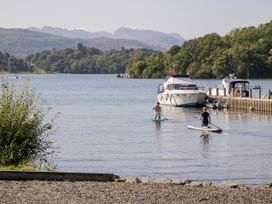 A lake scene with paddleboarders and a boat at 6 Waterside, White Cross Bay, Troutbeck Bridge