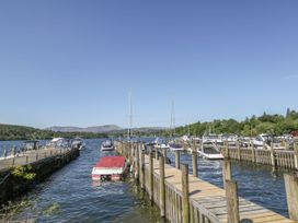 A dock with boats at a lake with hills in the background at 6 Waterside, White Cross Bay, Troutbeck Bridge