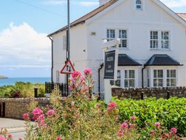 A house with a sign in front and flowers at Angorfa Apartment in Abersoch