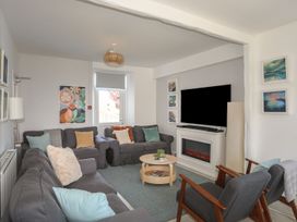 A living room with a television and seating arrangements at Angorfa Apartment in Abersoch