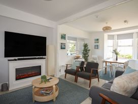 A living room with a fireplace and armchairs at Angorfa Apartment in Abersoch