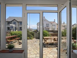 A view from a conservatory showing a table and benches at Angorfa Apartment in Abersoch