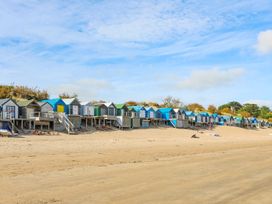 Several beach huts lined up on a sandy beach at Angorfa Apartment in Abersoch