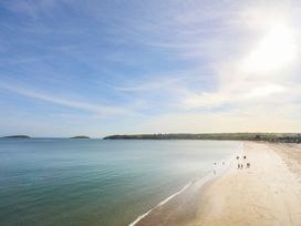 A beach scene with people walking along the shore at Angorfa Apartment in Abersoch