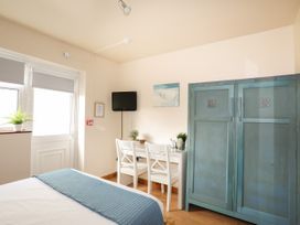 A bedroom with a bed, wardrobe, desk and television at Angorfa Apartment Abersoch