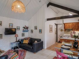A living room with a sofa and kitchen area at Honeypot Cottage Whitchurch Canonicorum