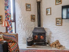 A living room with a wood stove and decorative pictures at Honeypot Cottage in Whitchurch Canonicorum