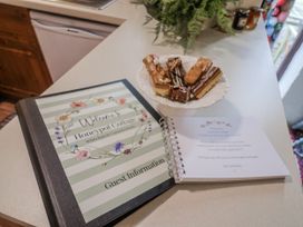 A guest information book and cake on a kitchen counter at Honeypot Cottage Whitchurch Canonicorum