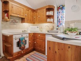 A kitchen with wooden cabinets and appliances at Honeypot Cottage in Whitchurch Canonicorum