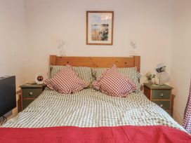 A bedroom with a bed and nightstand at Honeypot Cottage in Whitchurch Canonicorum