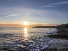 A beach with waves at sunset at Honeypot Cottage Whitchurch Canonicorum