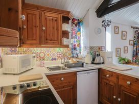 A kitchen with wooden cabinets and appliances at Honeypot Cottage Whitchurch Canonicorum