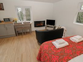 A living room with a microwave, table and chairs, and a tv at Heidiaway Lodge in Porth