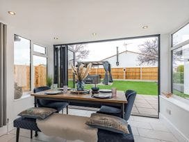 A dining room with a table and chairs overlooking the garden at 6 Tegafan Abergele