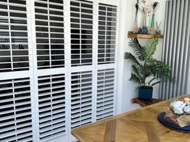 A dining room with sliding shutters and a table at 6 Tegafan in Abergele