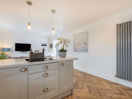 A kitchen with a stove and sink on the island at 6 Tegafan, Abergele