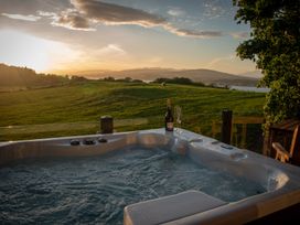 A hot tub with champagne and glasses overlooking a scenic view at Nethermill Lodges Port Glasgow
